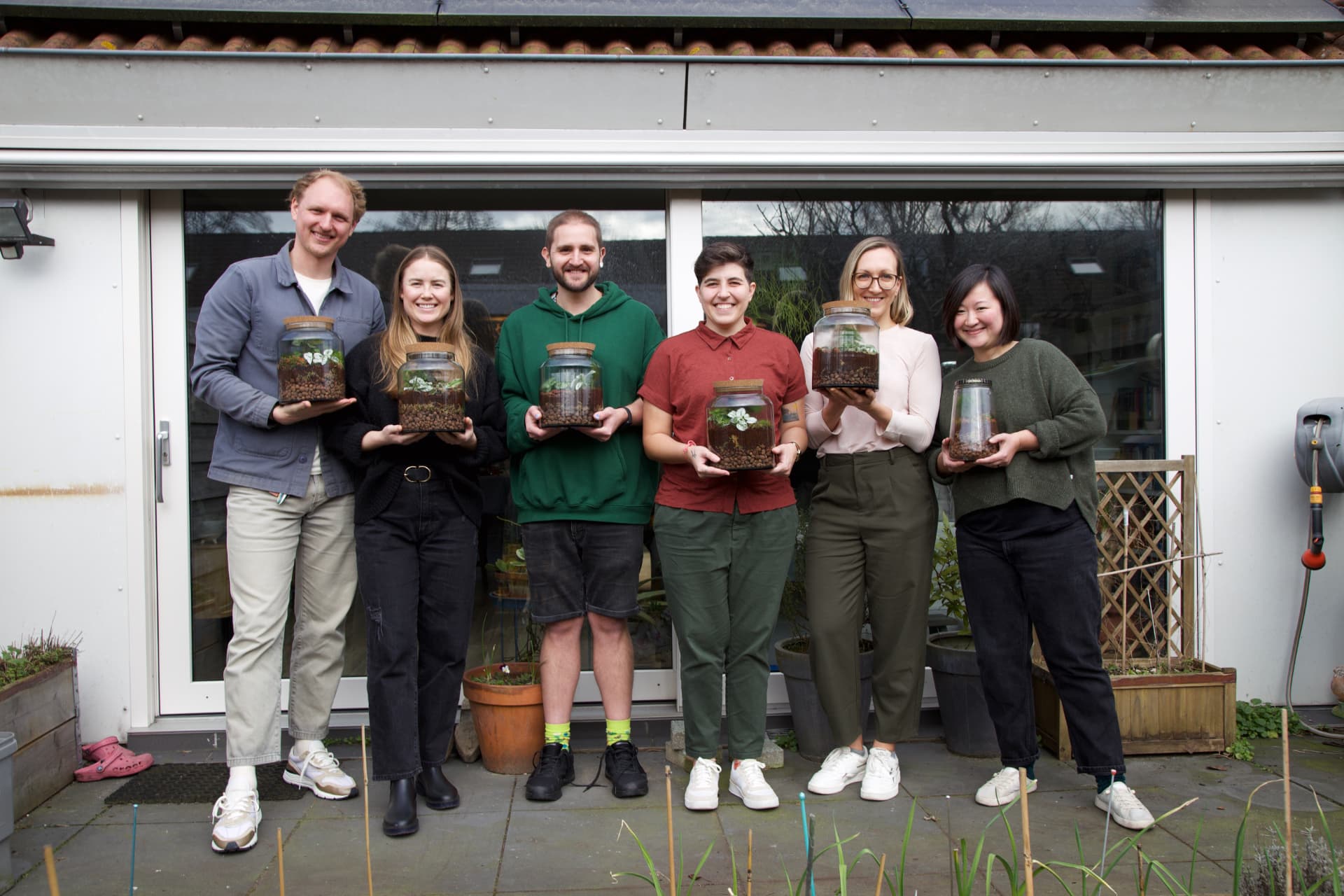 Participants of Amy's terrarium workshop holding the glass jar terrariums they made