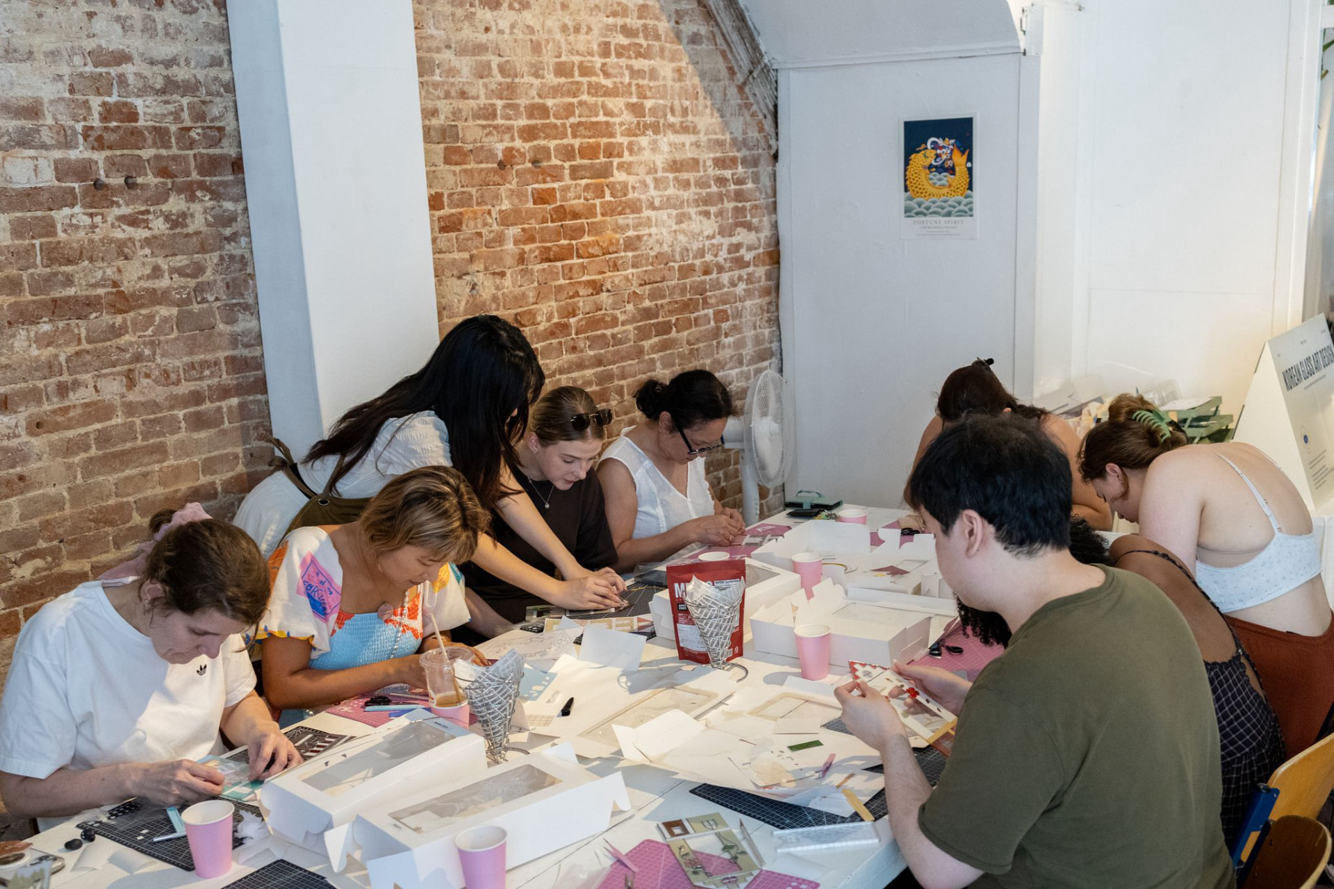 Participants making glass art together at a long workshop table